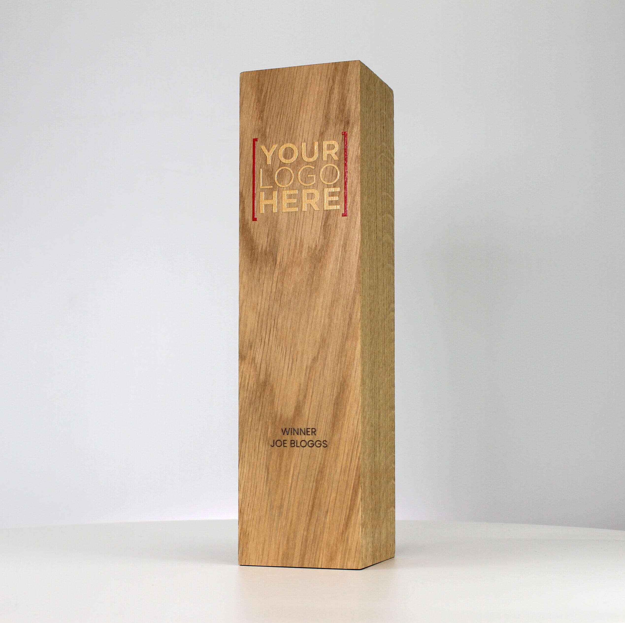 A small wooden trophy with a logo printed in gold and red, and winners name printed in black