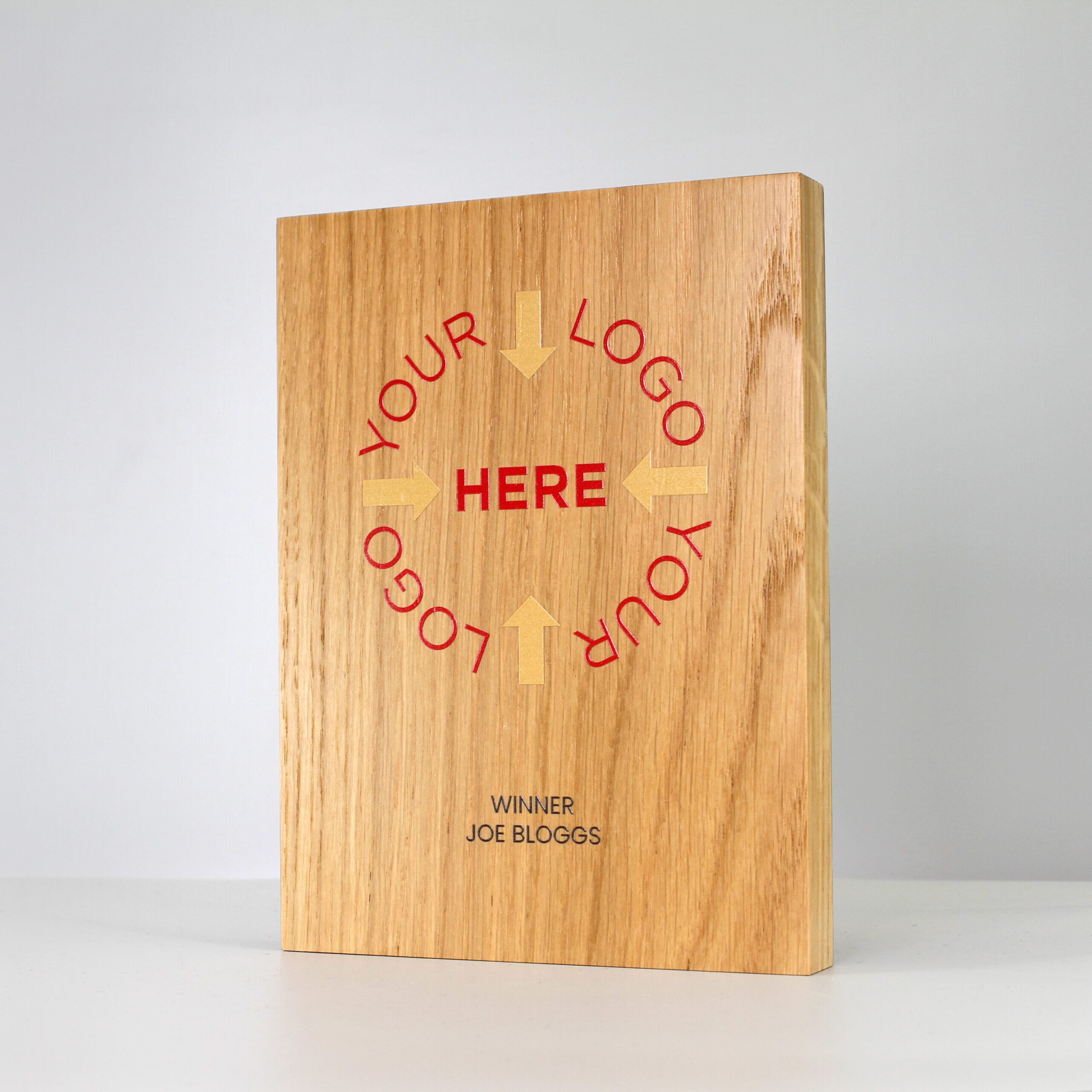A large custom wooden trophy with 'Your Logo Here' printed in gold and red, and 'Winner Joe Bloggs' printed in black