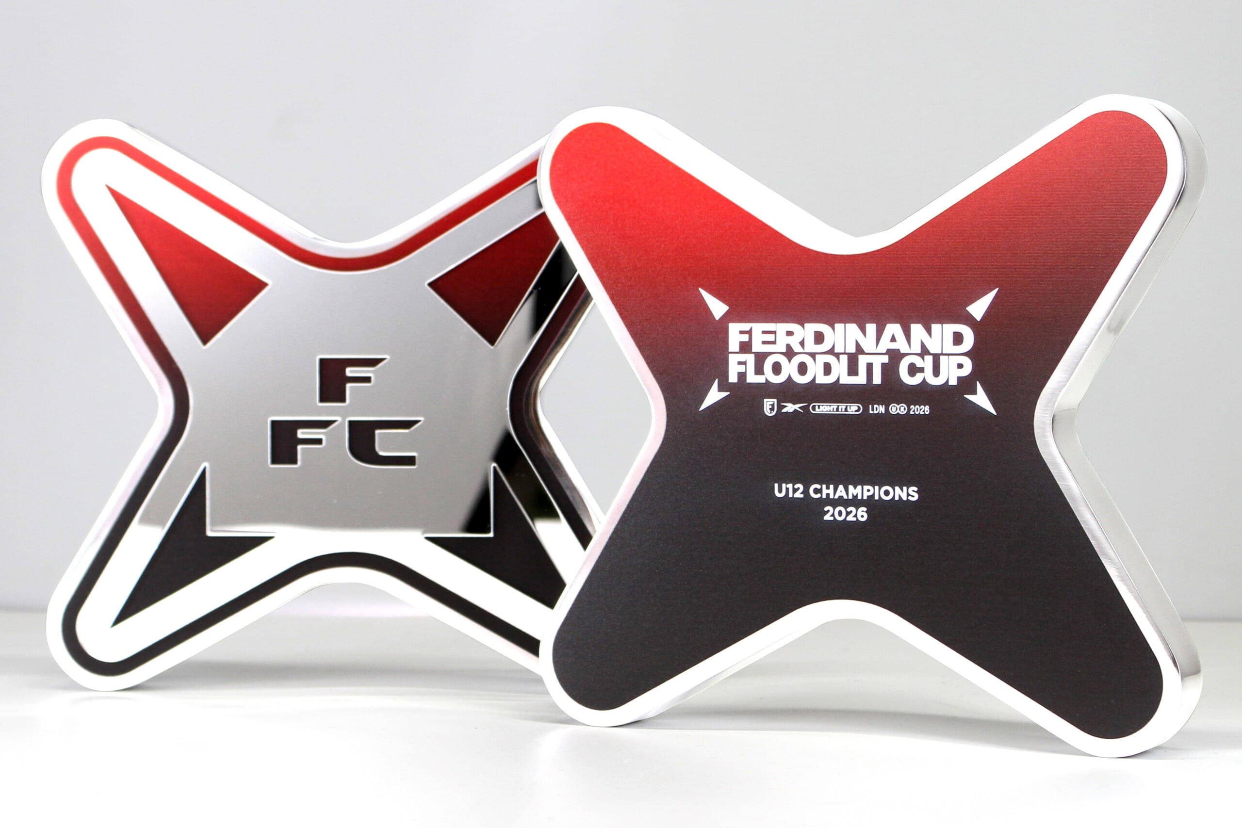 two custom metal trophies with red print and mirror acrylic detail